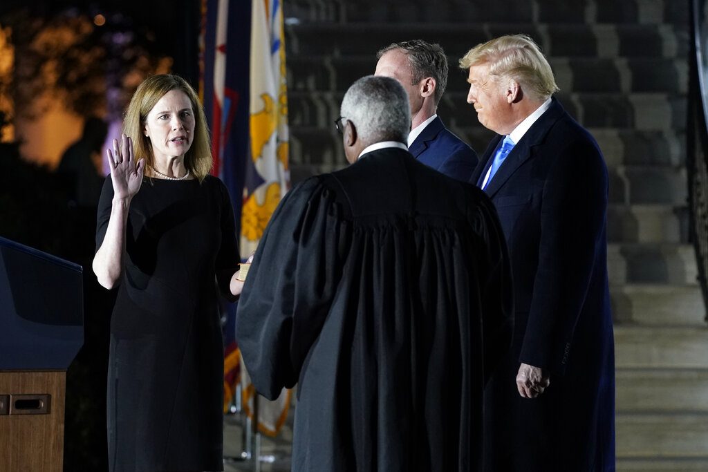 President Donald Trump watches as Supreme Court Justice Clarence Thomas administers the Constitutional Oath to Amy Coney Barrett on the South Lawn of the White House in Washington, Monday, Oct. 26, 2020, after Barrett was confirmed by the Senate earlier in the evening. (AP Photo/Patrick Semansky)