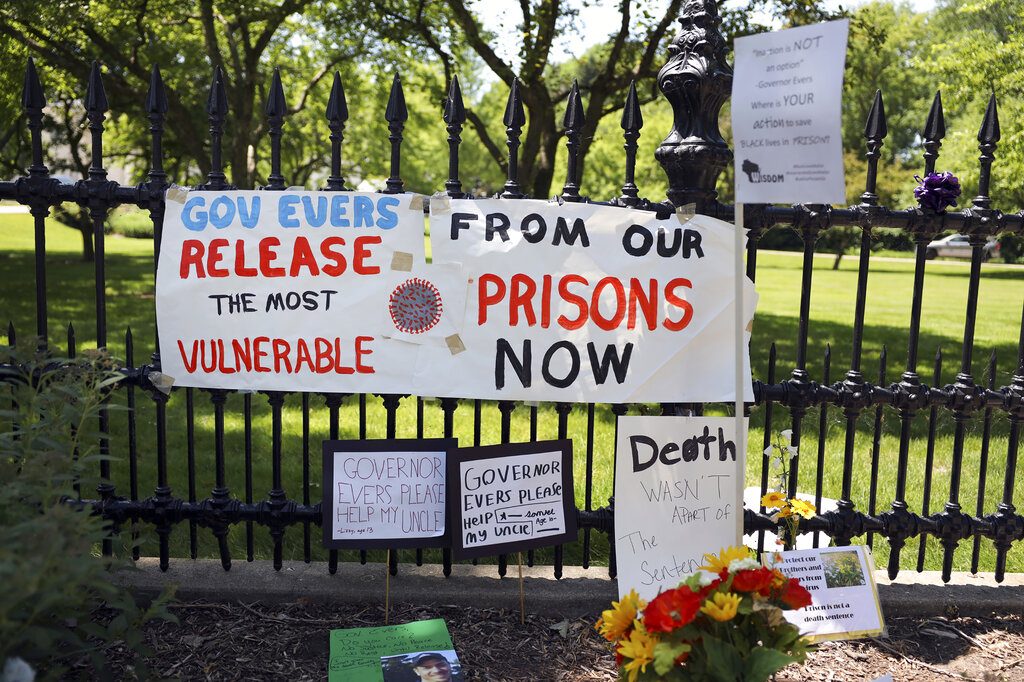 Signs and posters are left outside the Wisconsin governor's mansion in Maple Bluff, Wis., on June 18, 2020, as part of a "Drive to Decarcerate" event. Those attending urged Gov. Tony Evers to release inmates from Wisconsin's overcrowded prisons to slow the spread of COVID-19. Before the pandemic, Evers set a goal to cut the state's prison population in half. But 23 state prisons still exceed their designed capacity. (Coburn Dukehart/Wisconsin Watch via AP)