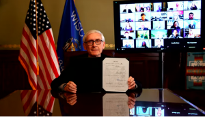 On Monday, Gov. Tony Evers displays the signed bill to restore pay parity for state public defenders. 