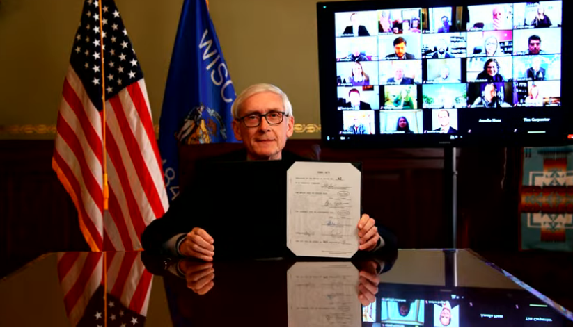 On Monday, Gov. Tony Evers displays the signed bill to restore pay parity for state public defenders.