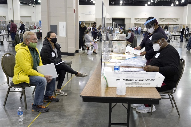 Election workers, right, verify ballots as recount observers, left, watch during a hand recount of presidential votes at the Wisconsin Center, in Milwaukee, on Nov. 20, 2020. (AP Photo/Nam Y. Huh, File)
