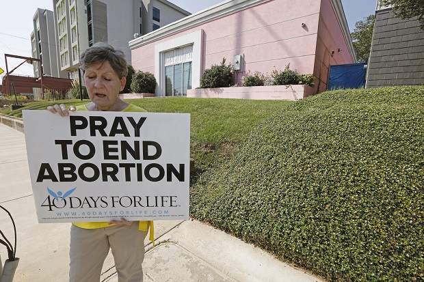 An abortion opponent sings to herself outside the Jackson Womens Health Organization clinic in Jackson, Mississippi, on Oct. 2, 2019. The Supreme Court has agreed to hear a potentially ground-breaking abortion case, and the news is energizing activists on both sides of the contentious issue. (AP Photo/Rogelio V. Solis, File)