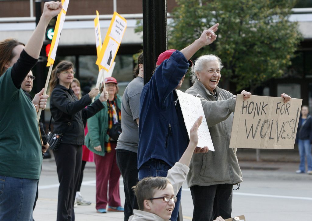 FILE - In this Oct. 15, 2013, file photo, Ann Emerson, of Madison, far right, holds a sign during a wolf hunt protest outside the Capitol in Madison, Wis. A coalition of animal rights groups planned to file a lawsuit Tuesday, Aug. 31, 2021, to stop Wisconsin's fall wolf hunt. (Michelle Stocker/The Capital Times via AP, File)